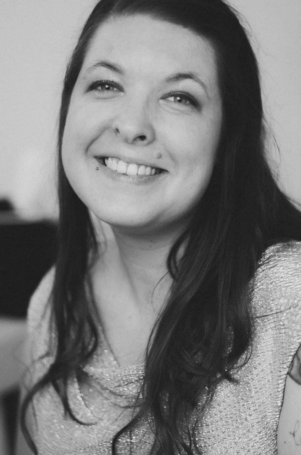 Black-and-white portrait of a smiling woman with long dark hair wearing a sparkly top