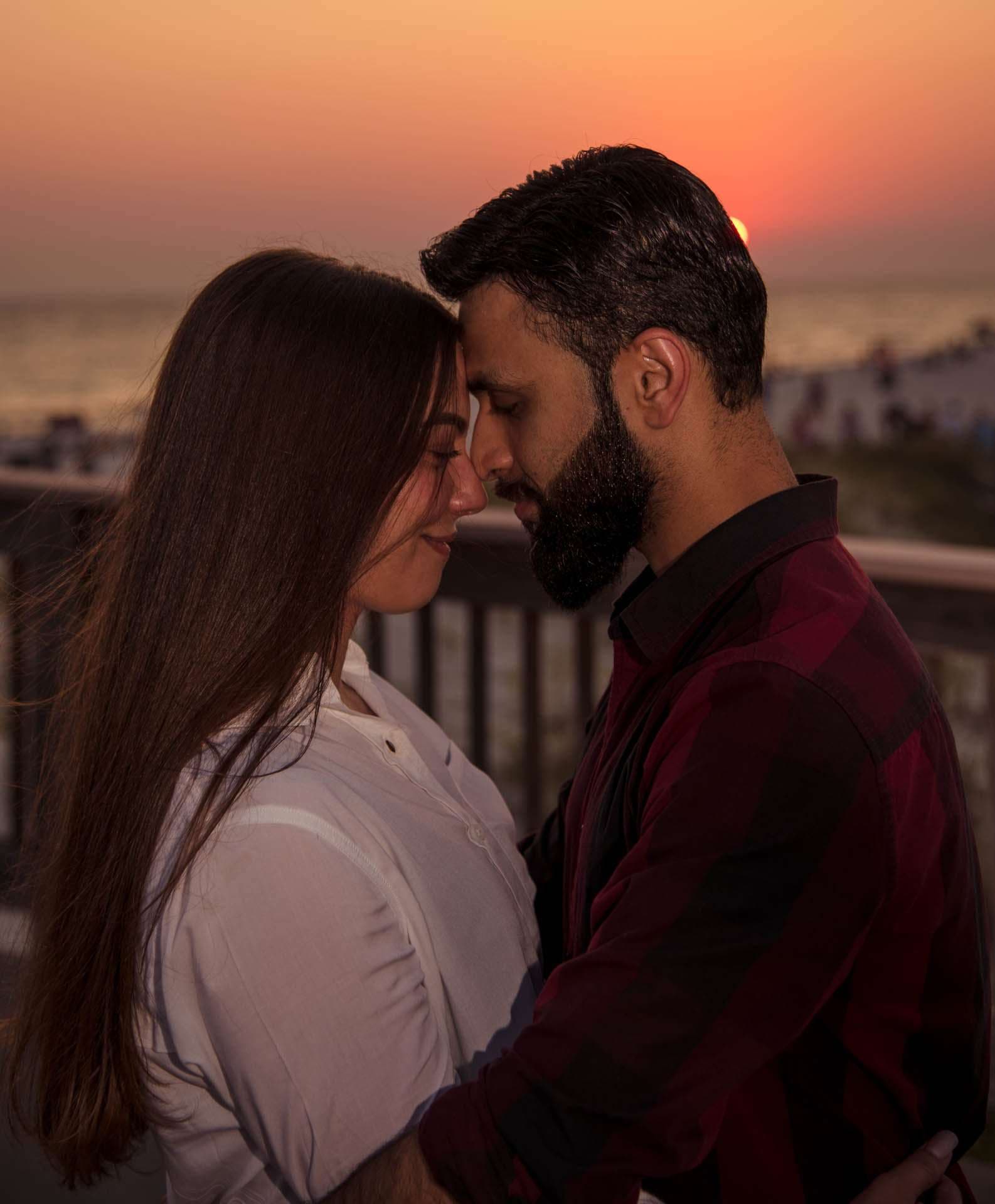 Couple standing forehead to forehead on the Panama City Beach City Pier at sunset, the woman smiling with eyes closed
