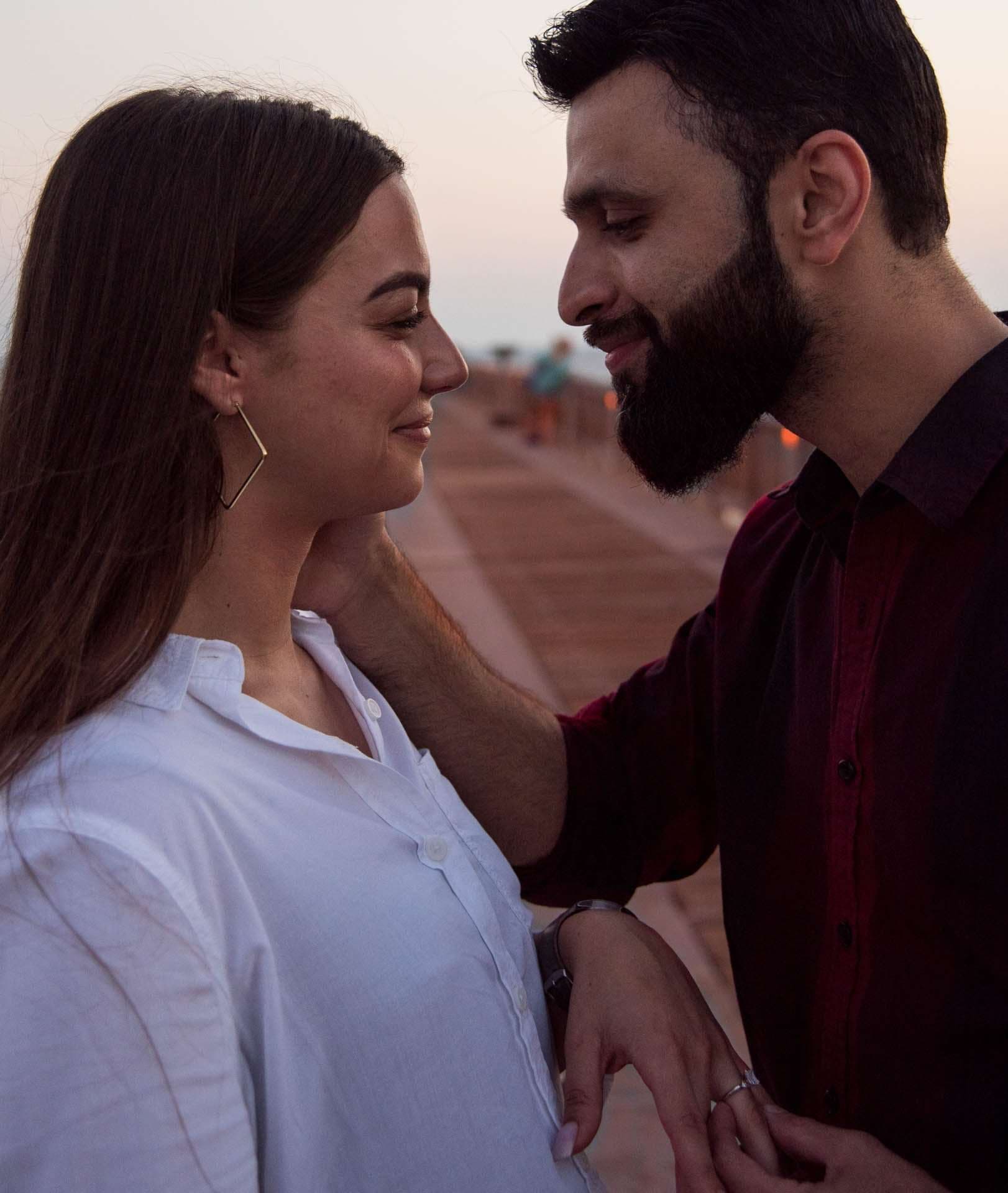 Bearded man gently touching a smiling woman's face as they gaze at each other on the Panama City Beach City Pier