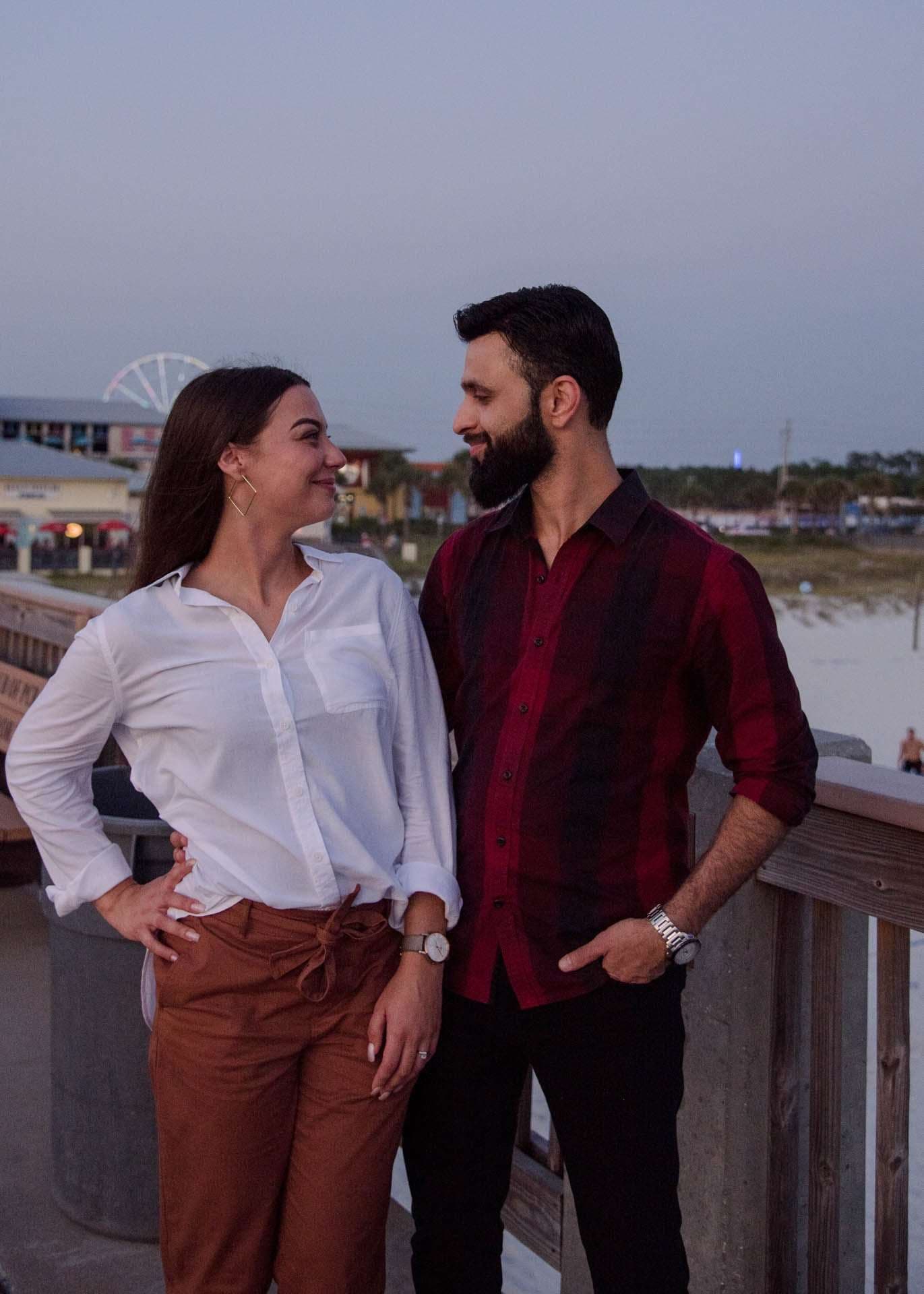 Couple smiling at each other on the Panama City Beach City Pier, Ferris wheel in the background