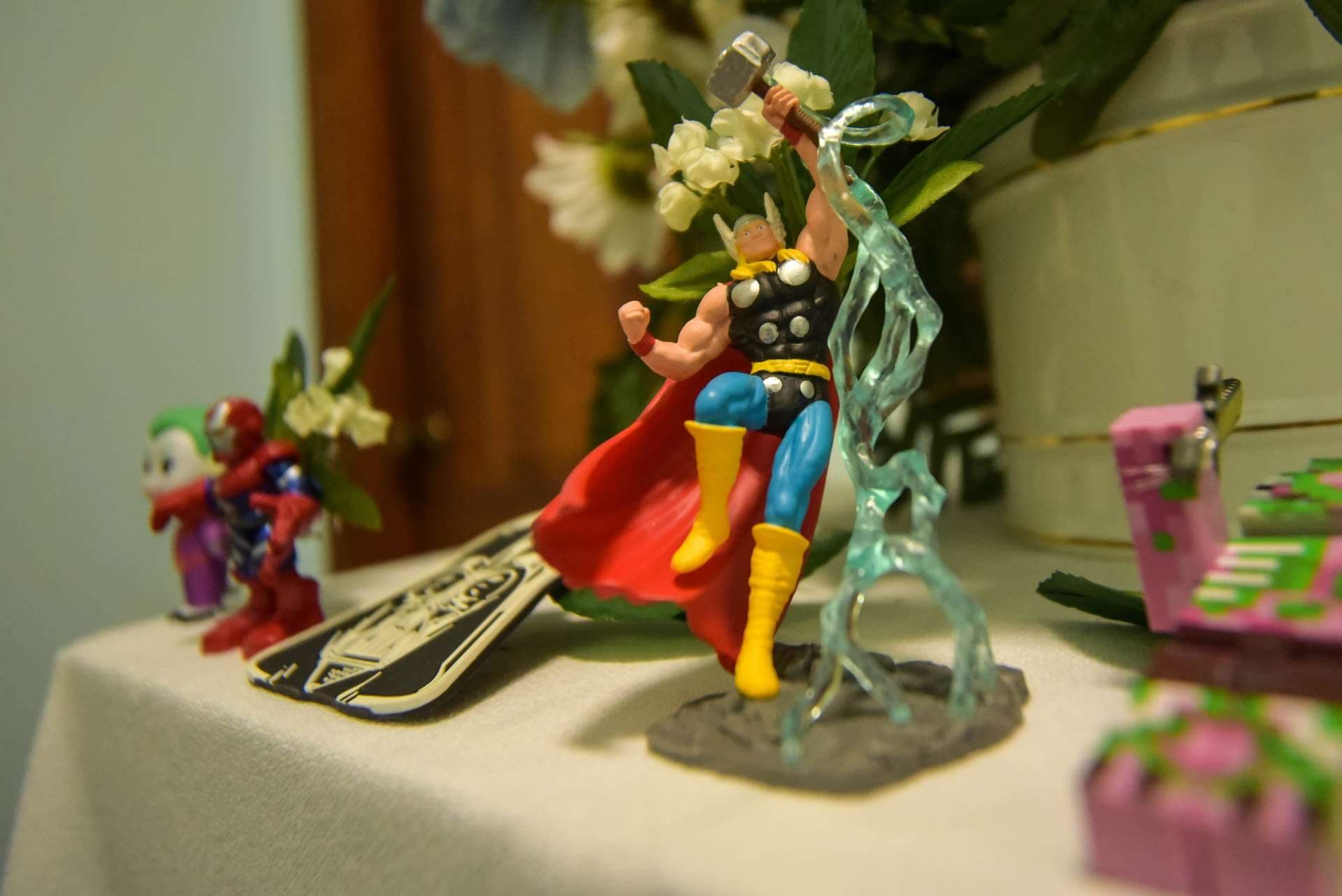 Thor and other superhero figurines on a reception table beside white flowers