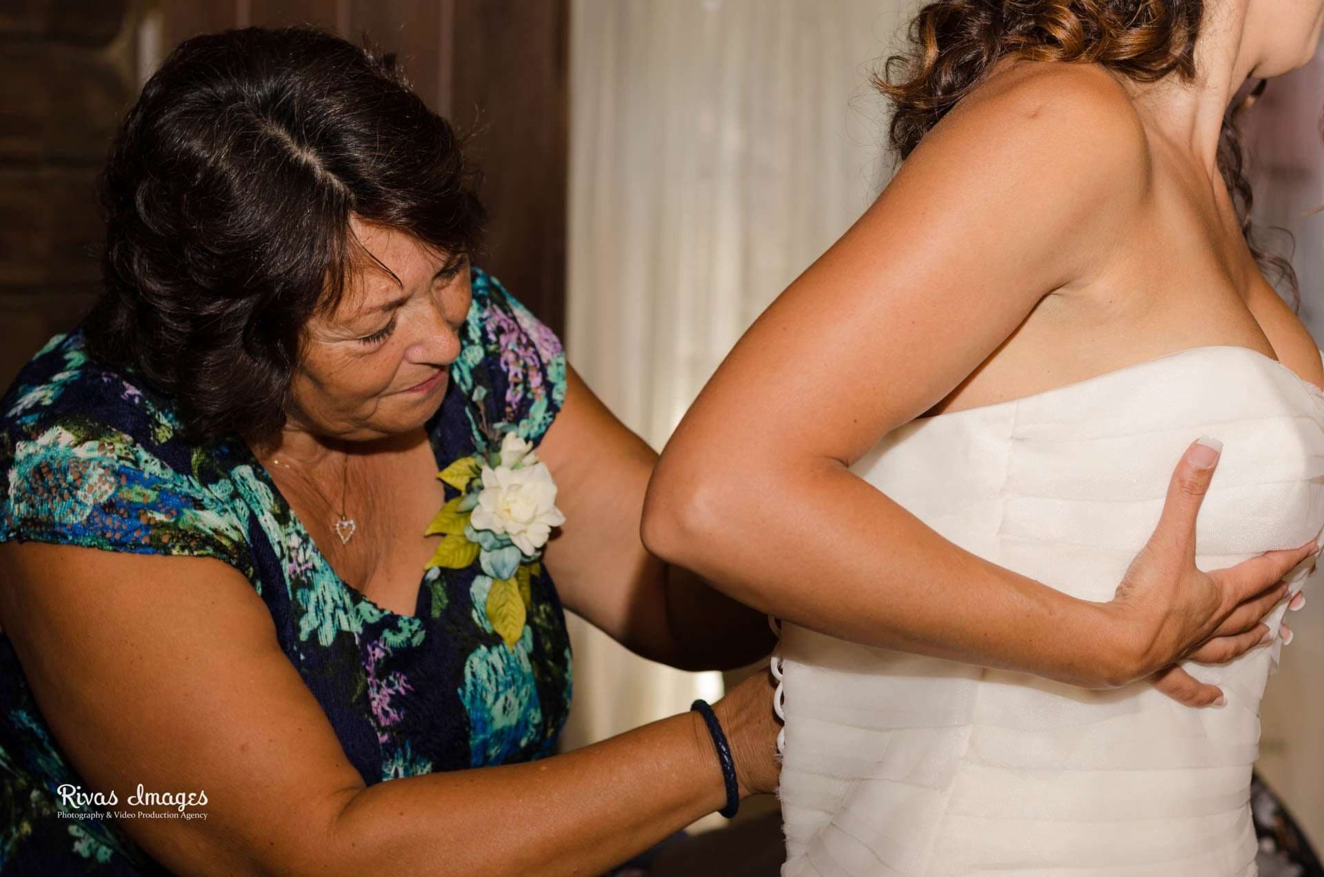 Woman in floral dress with a white corsage helps a bride in a strapless gown get ready at Camp Helen State Park